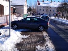 Pojazd marki Renault zaparkowany na całej szerokości chodnika.